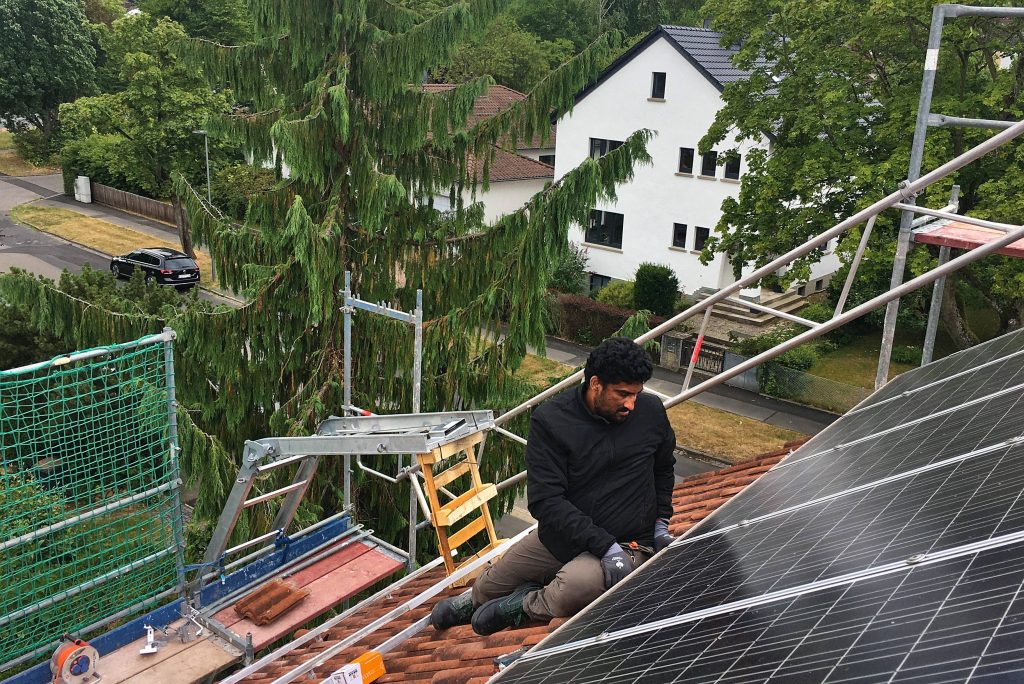 Laie auf dem Dach einer Selbstbaugemeinschafts-Photovoltaik-Baustelle